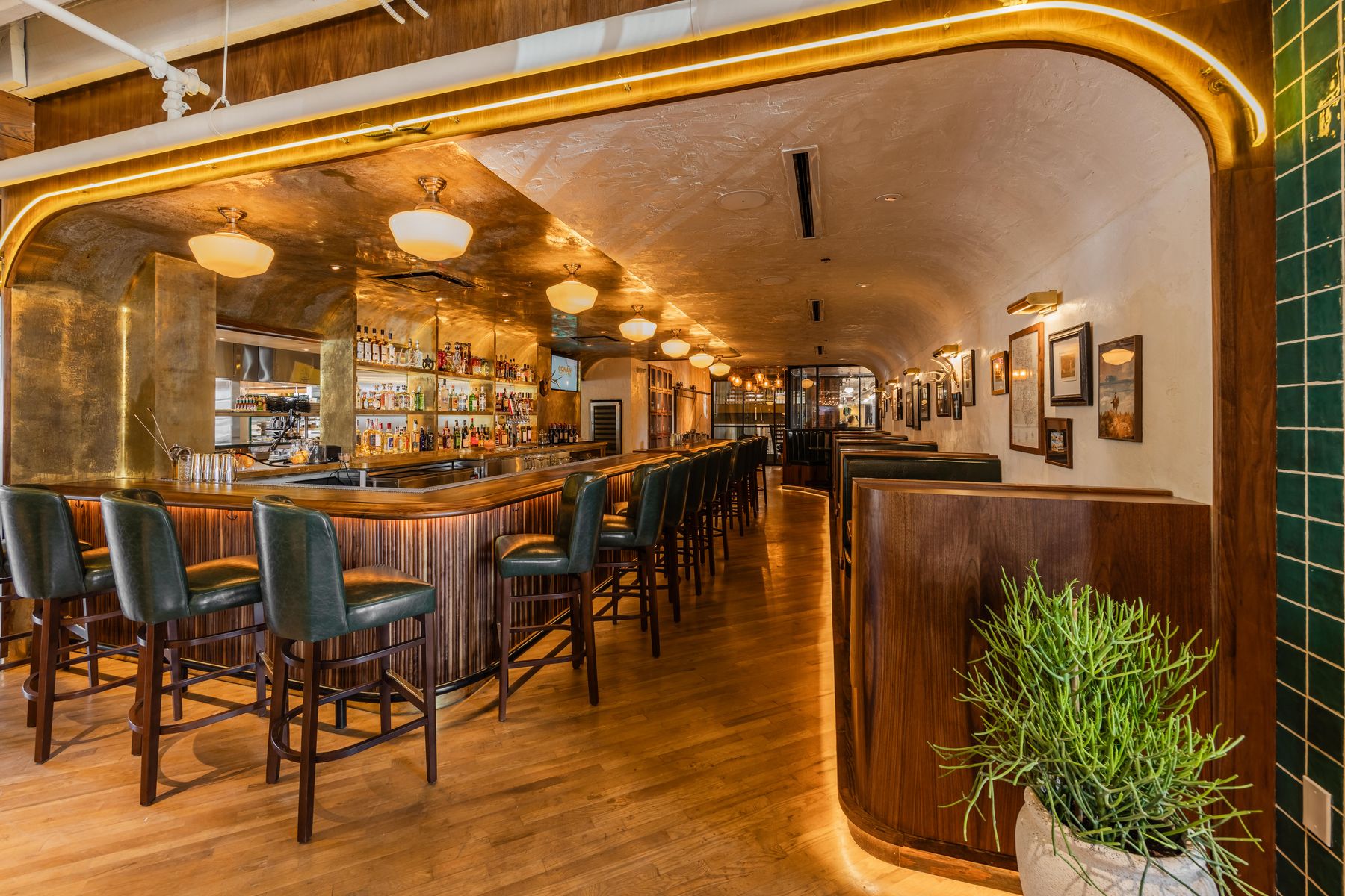 Bar at Culpepper Cattle Co. in Deep Ellum — walnut tambour bar front, brass ceiling, and green leather seating