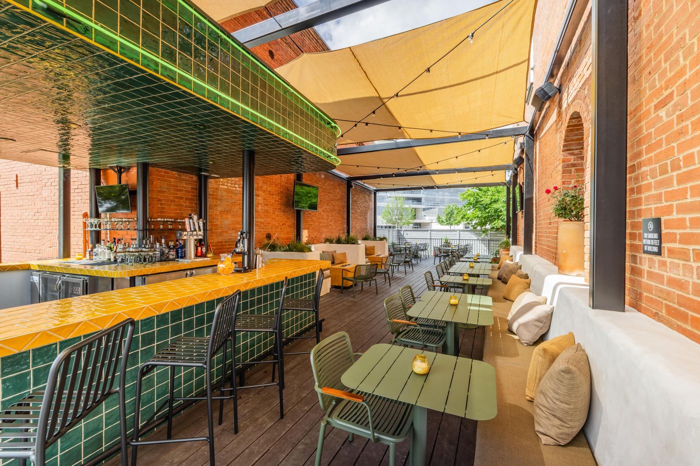 Patio bar at Culpepper Cattle Co. with green and yellow glazed tile under shade sails